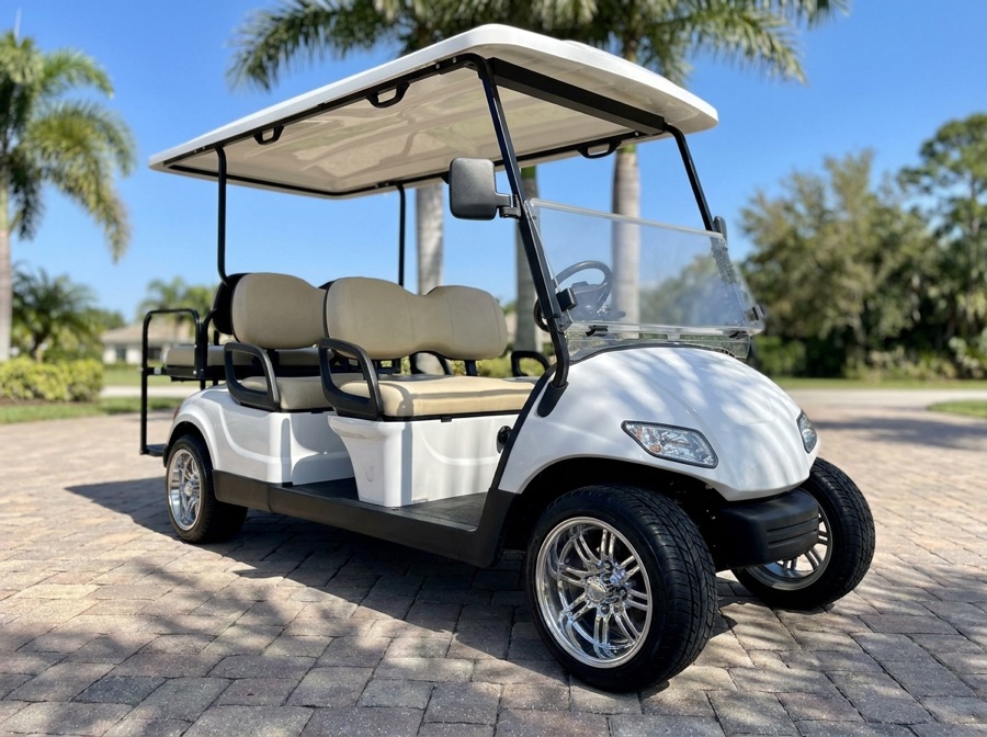 White four-seat golf cart on a sunny driveway